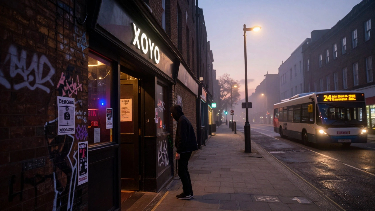 A lone person leaving XOYO at dawn, the club's glow fading behind graffiti-covered walls.